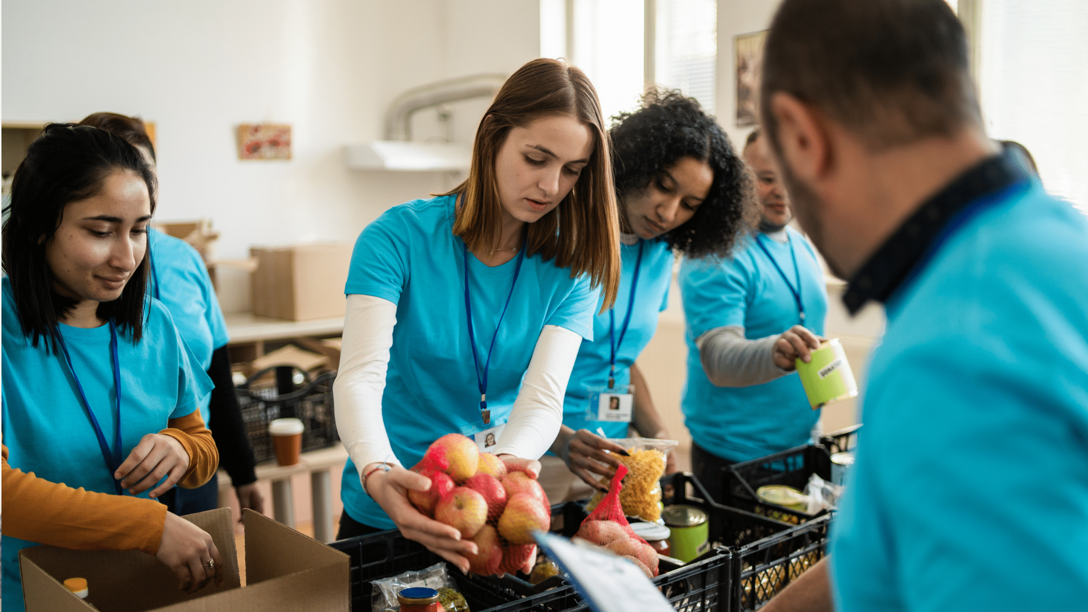 Students placing apples in a basket at a food pantry