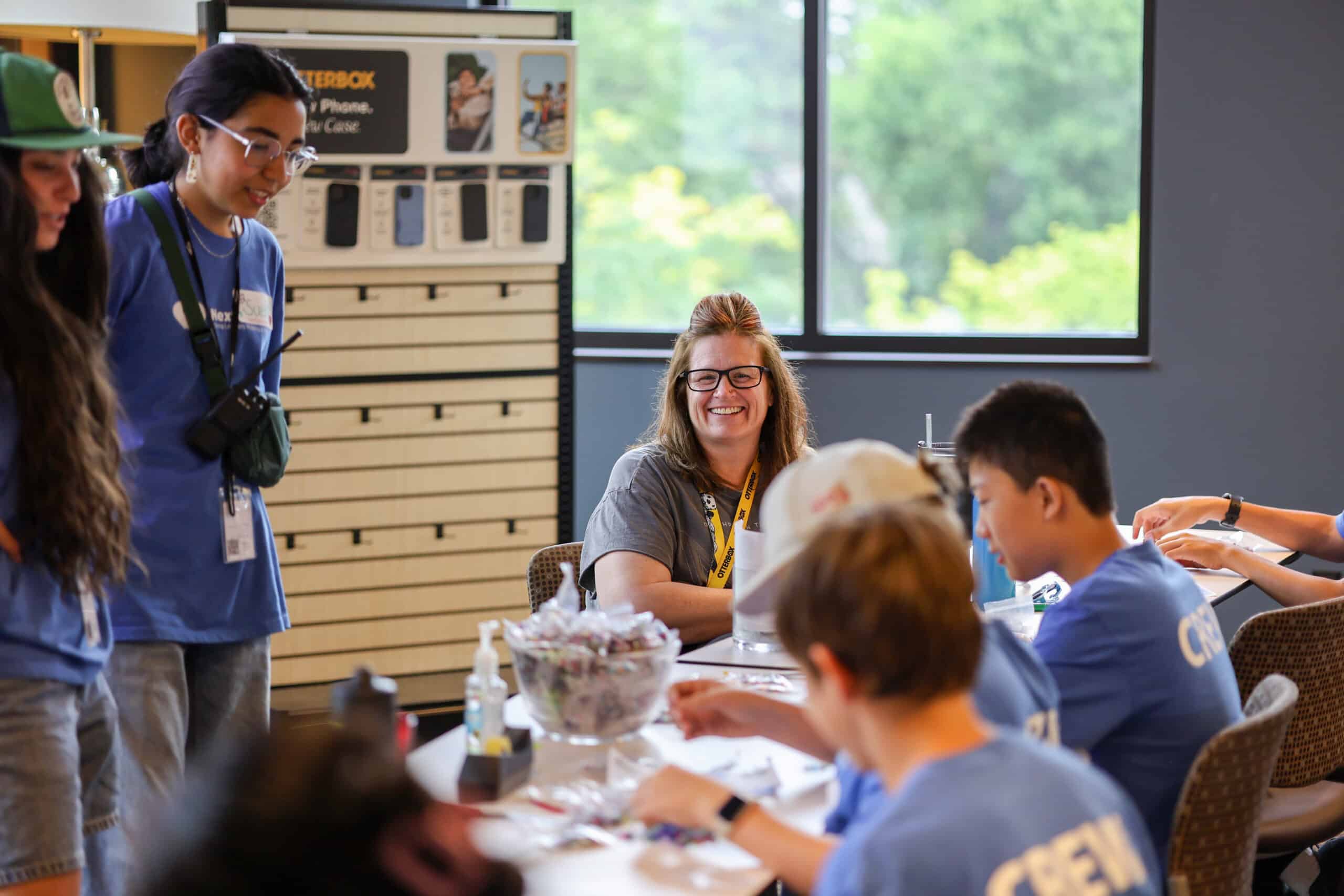 Woman smiling facing students working on volunteer project in classroom setting.