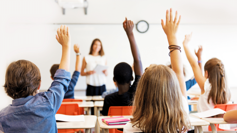 Students in a classroom raising their hands